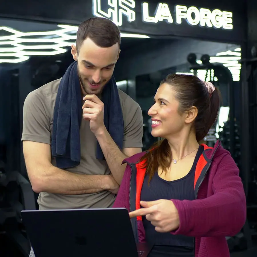 Coach sportif expliquant exercice câbles poulies pectoraux client Forge One Fitness Neuchâtel